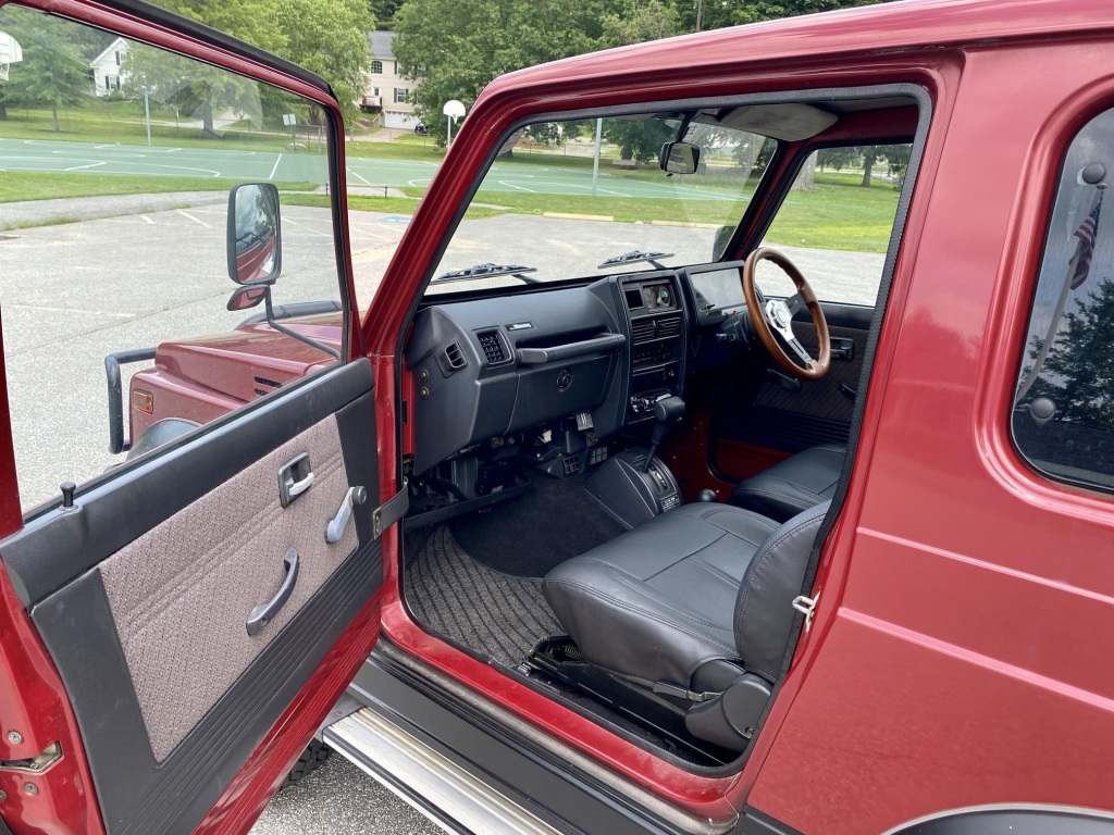 Vista lateral del interior de un Suzuki Jimny Sierra 4x4 rojo de 1994 con asientos de cuero
