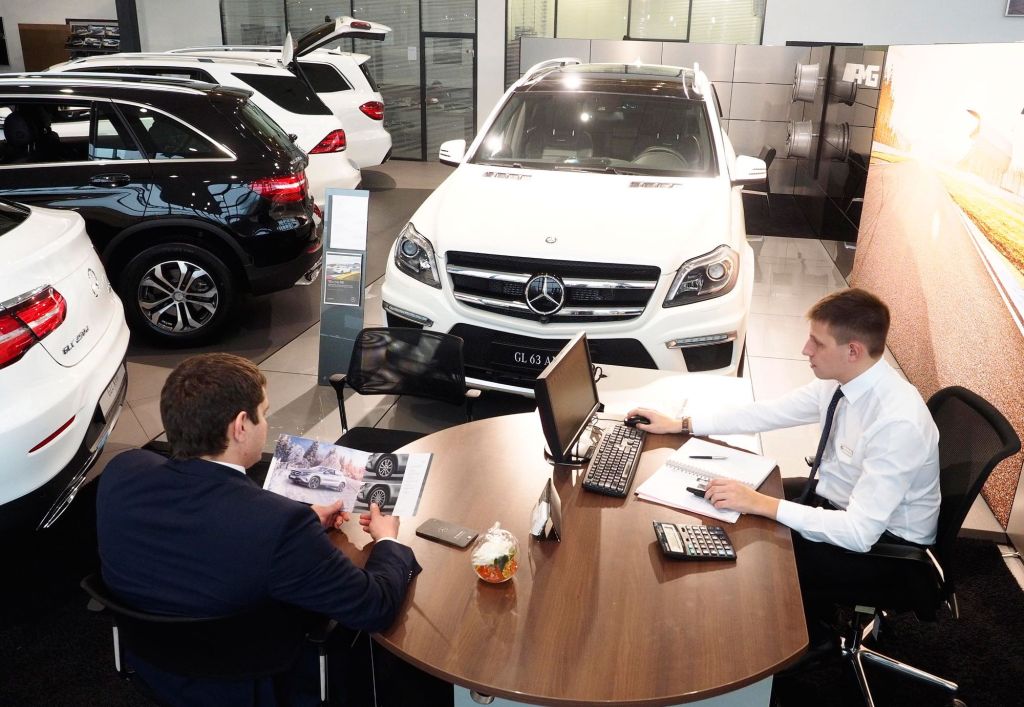 Un vendedor de coches se sienta con un cliente en un concesionario.
