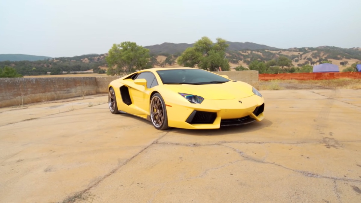 Un Lamborghini Aventador amarillo con ruedas de color bronce preparándose para una carrera de aceleración.