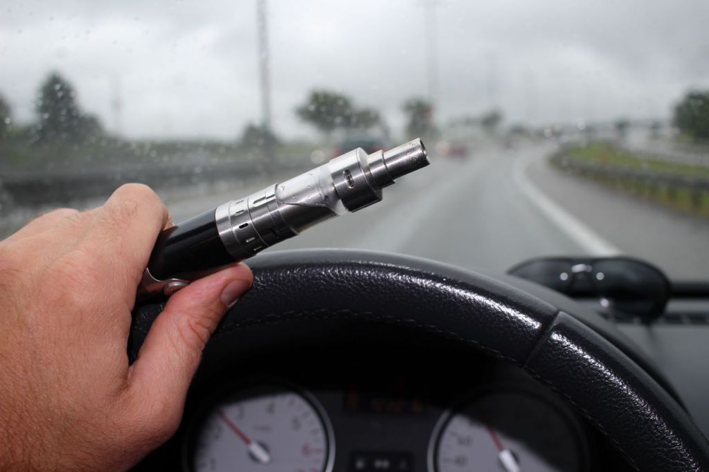 Un conductor fumando al volante de un coche en movimiento