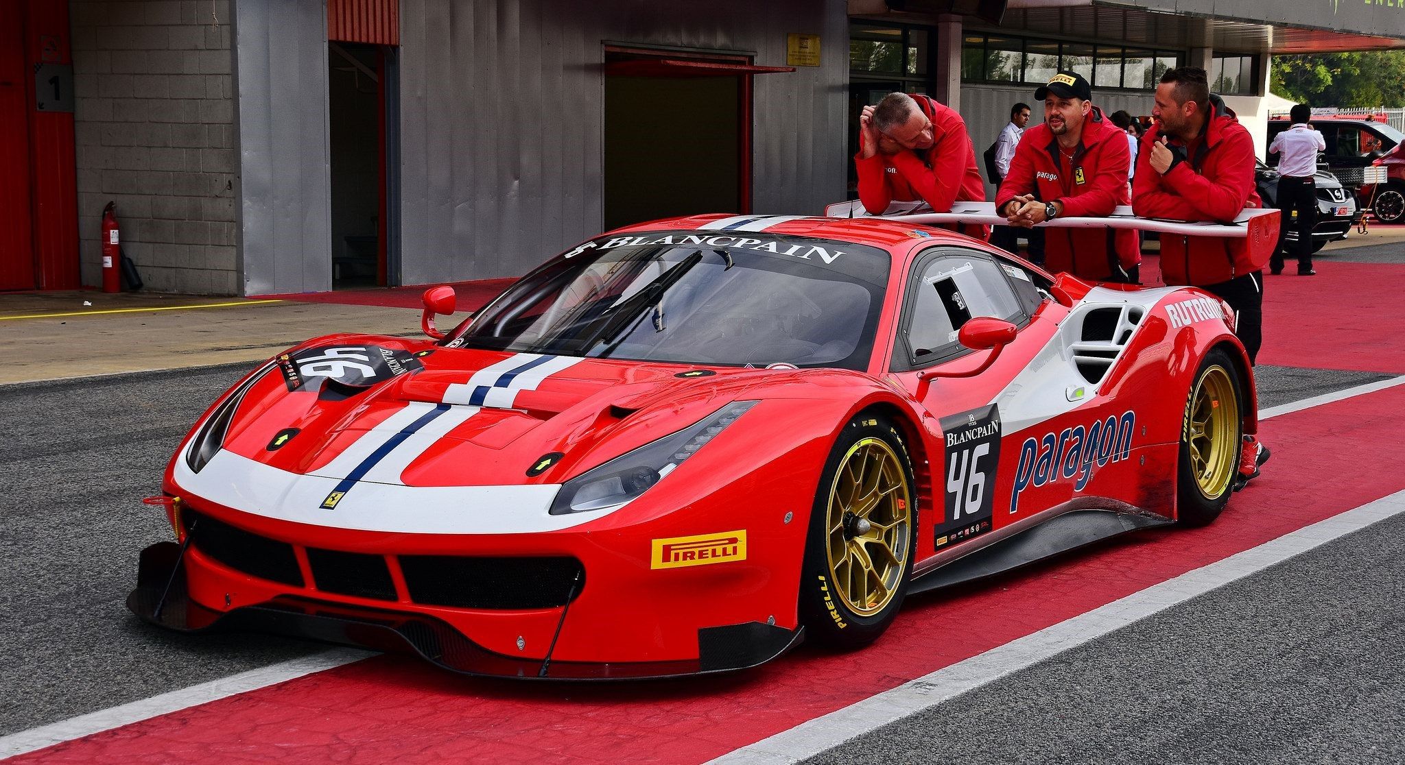 Pilotos de Ferrari apoyados en un coche de carreras