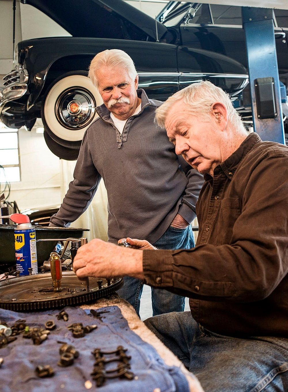 Dos viejos amigos inspeccionando juntos las piezas del coche