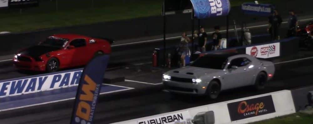 Dodge Challenger vs Ford Mustang carrera de aceleración, noche, vista del cuarto delantero en la pista