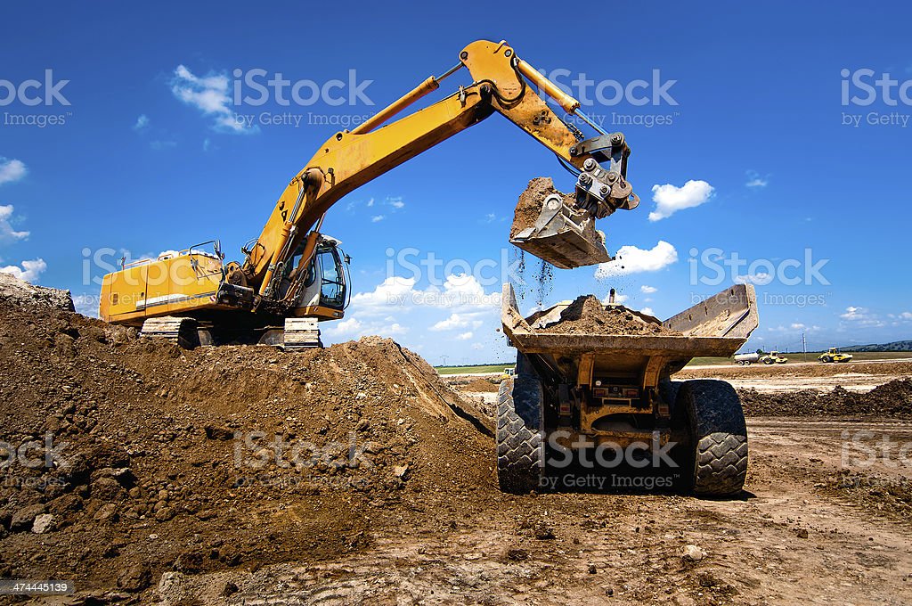 Camión industrial excavador moviendo tierra y descargando int Camión industrial excavador moviendo tierra y descargando en un camión dumper retroexcavadora fotos de stock, fotos e imágenes libres de derechos